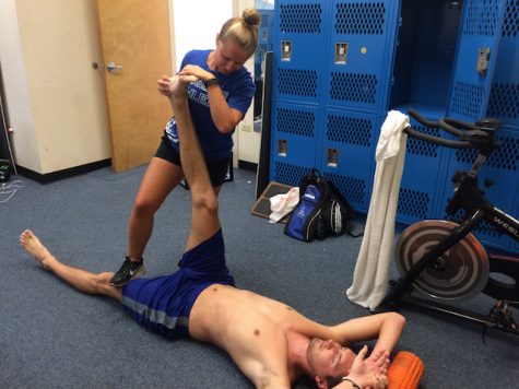 Graduate assistant trainer, Kelsey Tomaszewski, stretching a Chaminade athlete in the training room. 
