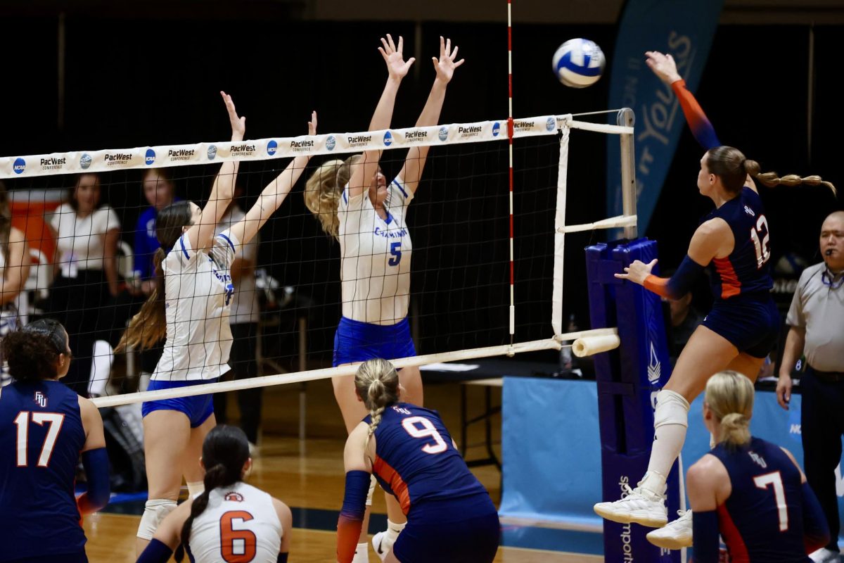 Cambria Wates (#12) spiking it over Cahminade players (Left to Right) Tabby Allen and Audrah Johnson.
