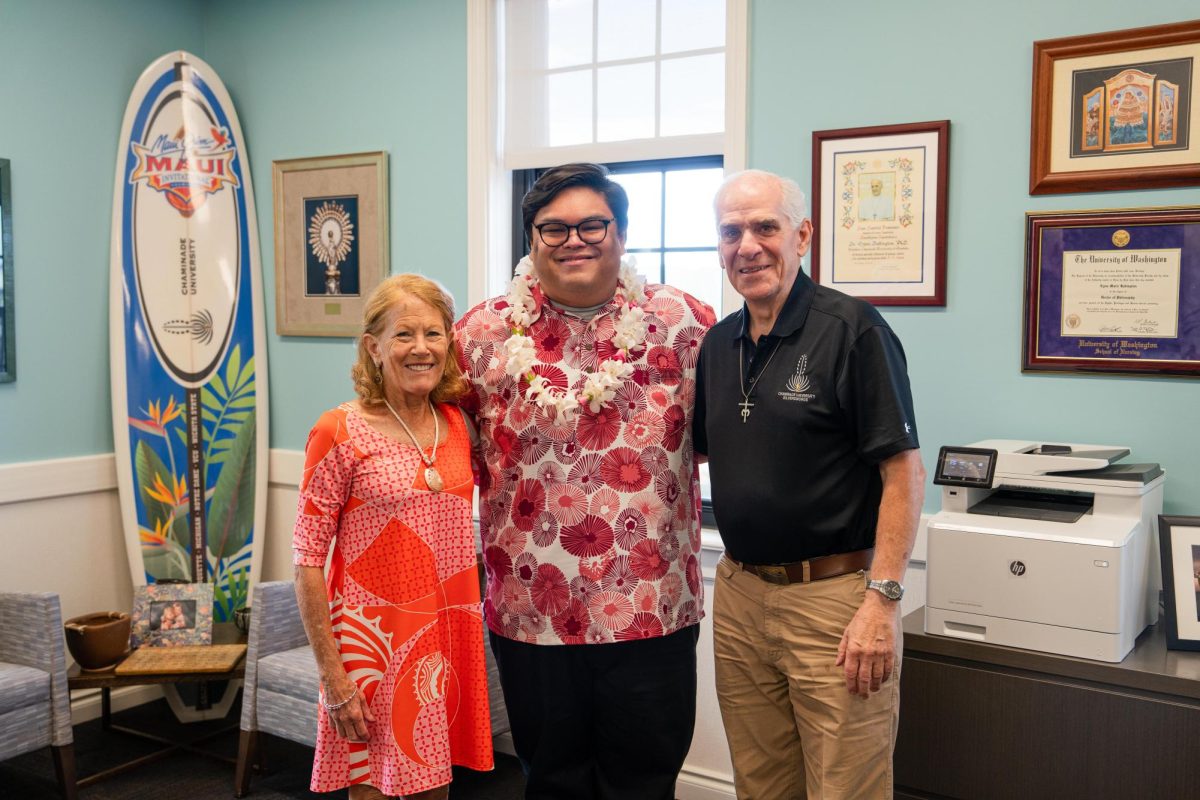Dustyn Ragasa (center) with Chaminade president Lynn Babington and vice president Rev. Martin Solma, S.M., learning he won the Chaminade Award. (Photo courtesy of Chaminade University Communications and Marketing)